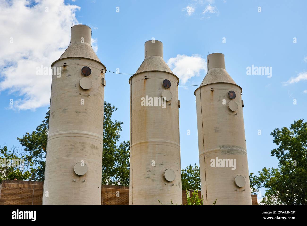 Silos industriels contre ciel bleu avec nuages épars, vue au niveau du sol Banque D'Images