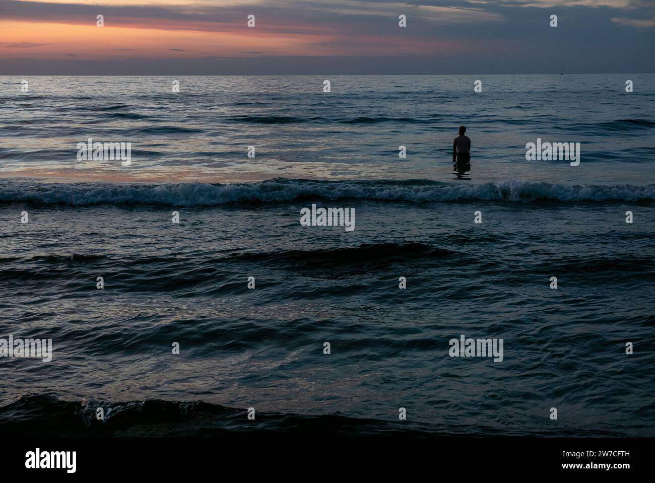 08.09.2018, Pologne, Kolobrzeg, Poméranie occidentale - Sillhouette d'un vacancier debout dans l'eau sur la côte Baltique au coucher du soleil. 00A180908D0993CAROE Banque D'Images