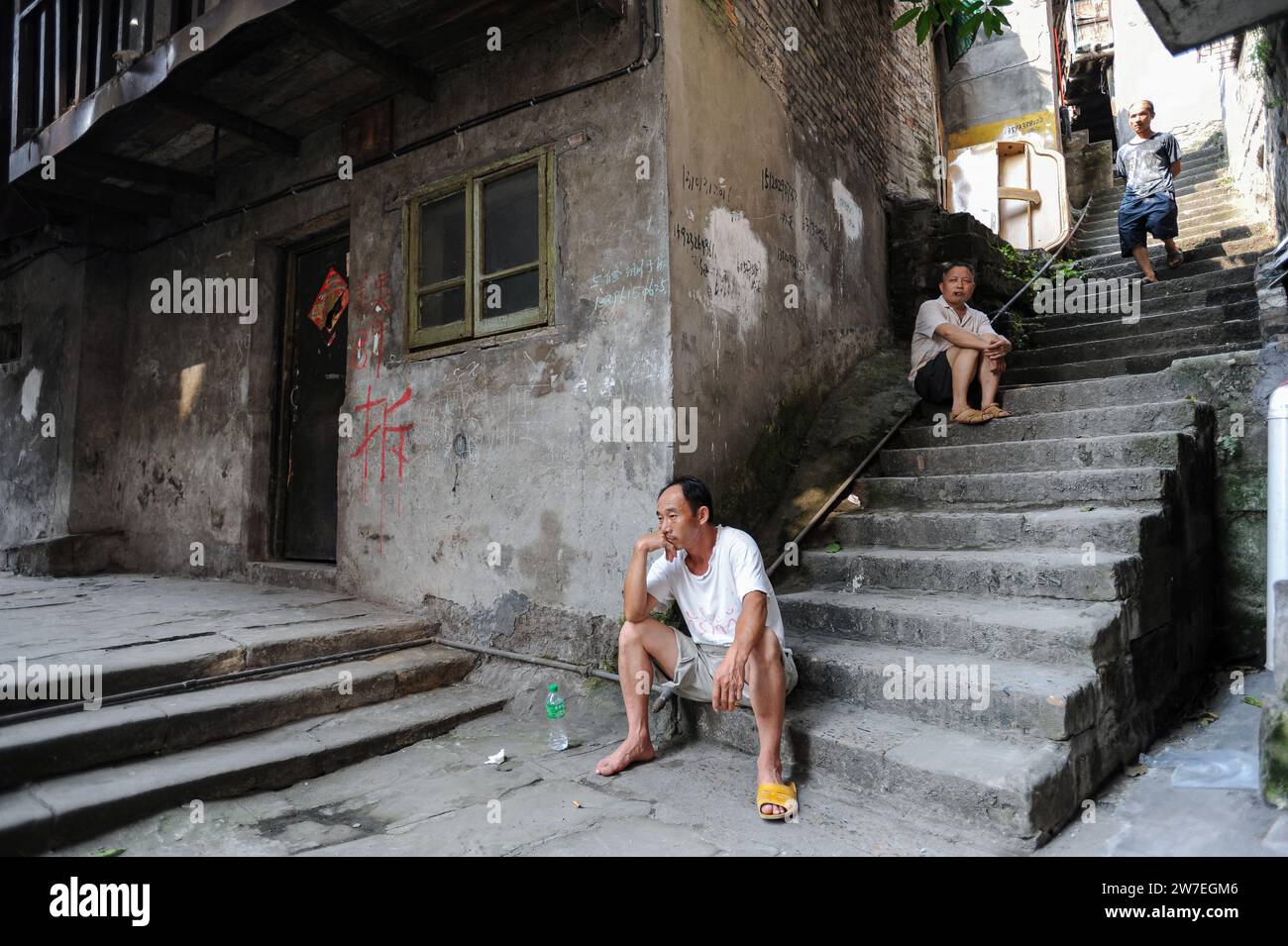 04.08.2012, Chine, Chongqing, - des hommes sont assis sur les marches devant un ancien immeuble résidentiel dans la vieille ville de Shibati dans le quartier Yuzhong de Th Banque D'Images