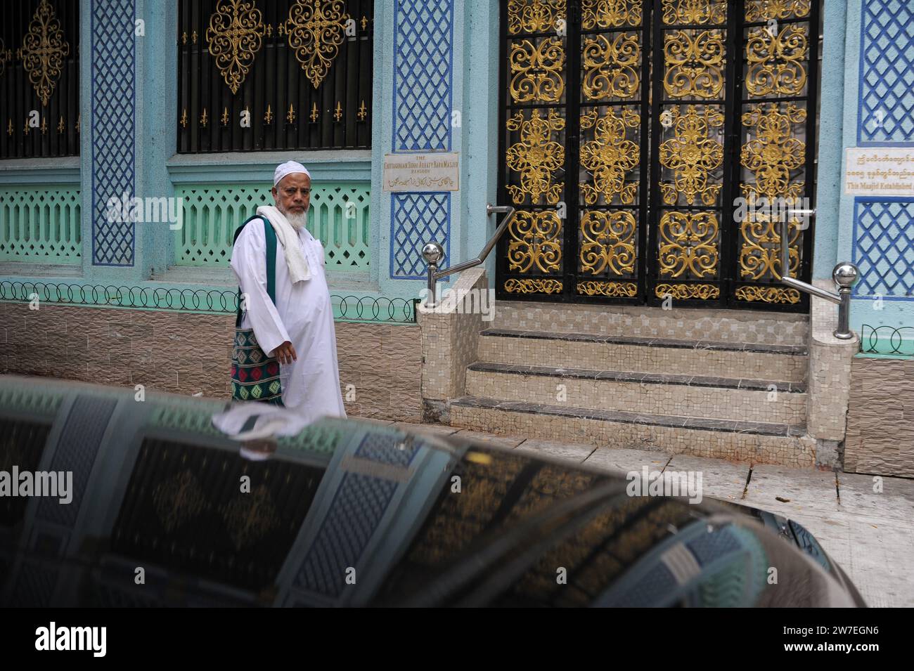 21.02.2014, Myanmar, Yangon, - Un musulman fervent en tenue traditionnelle passe devant la mosquée sunnite chittagonienne Arkaty Bara Masjid dans le centre-ville de Banque D'Images