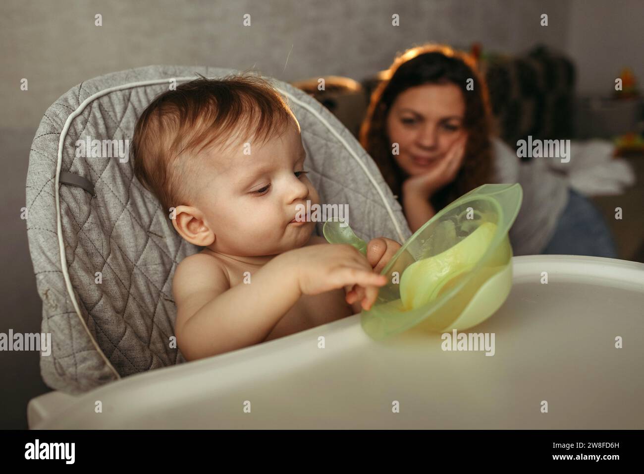Un petit enfant mange de la purée de légumes. Maman regarde le bébé. Banque D'Images