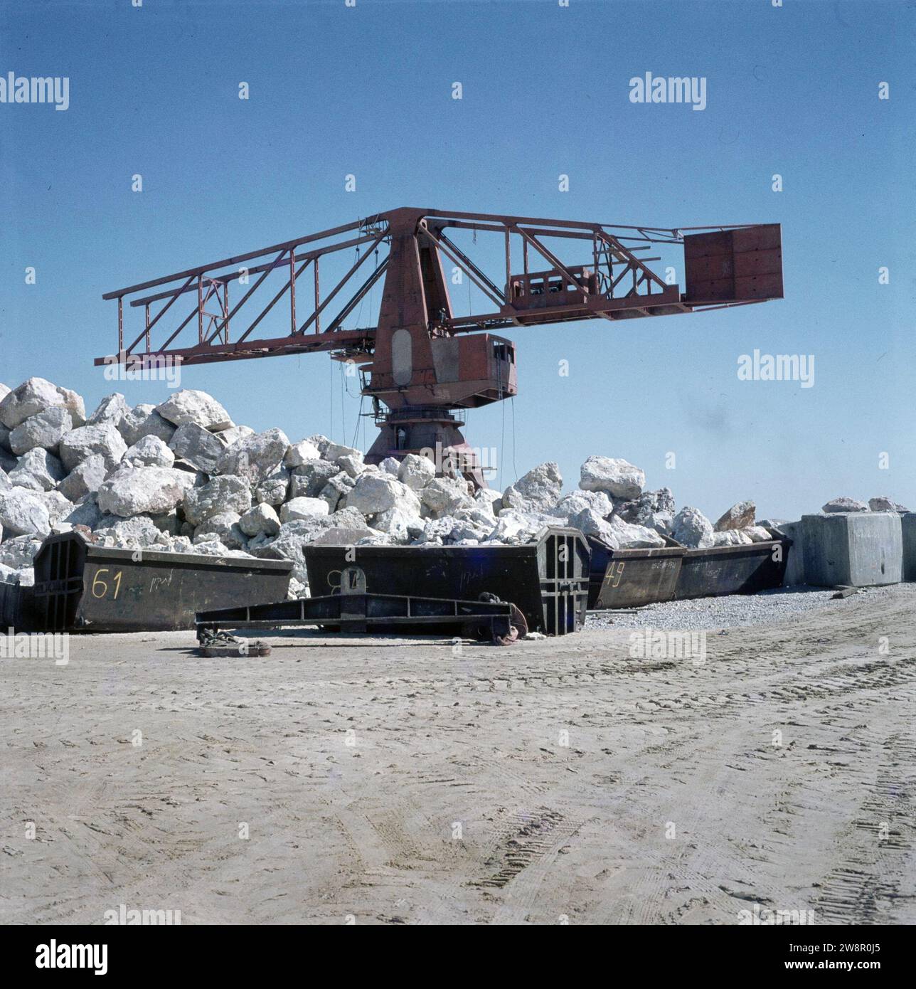 Ashdod. Construction portuaire : grue avec conteneurs avec de grands rochers sur un site près du port ca. non daté Banque D'Images