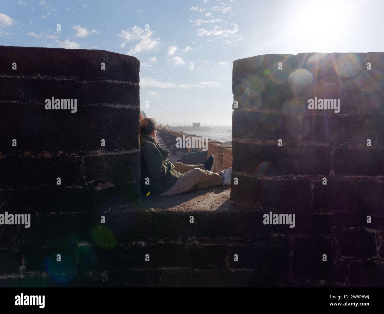 Les touristes sont assis dans les murs de la ville au-dessus des canons à canon au fort à Essaouira alias «la ville venteuse», Maroc. 21 décembre 2023 Banque D'Images