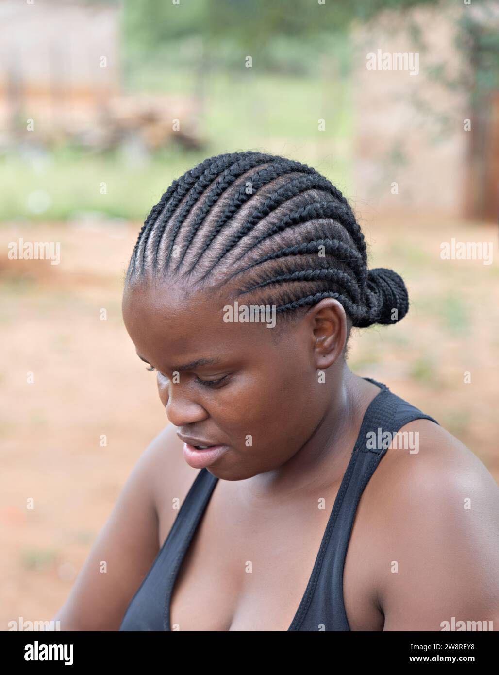 femme africaine avec des tresses dans le village debout dans la cour en face de la maison Banque D'Images