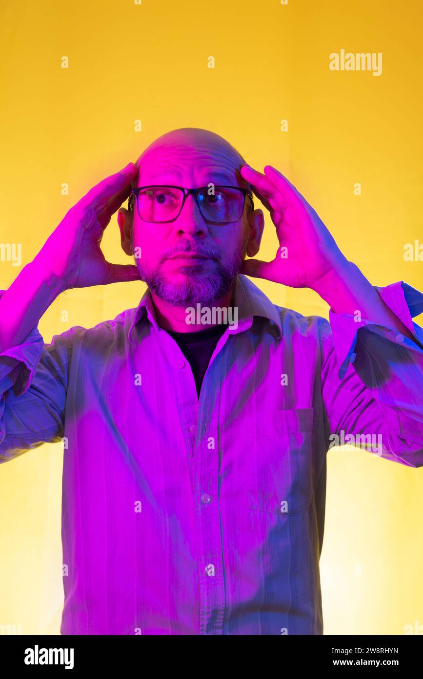 Homme chauve, barbu portant des lunettes faisant des gestes avec ses mains. Isolé sur fond jaune. Banque D'Images