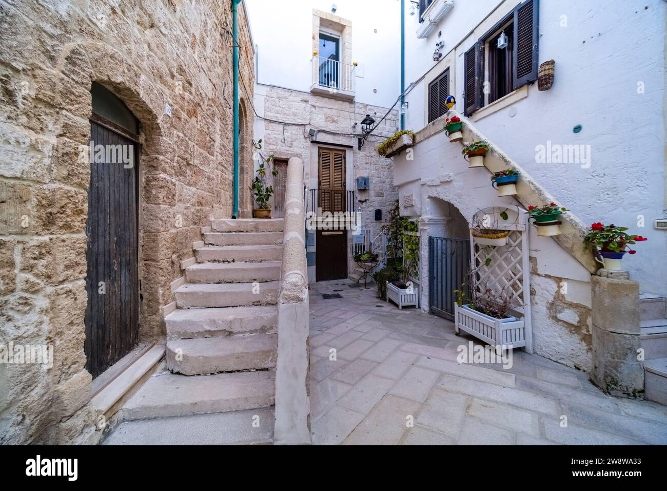Scène de rue avec une petite cour entre maisons, escaliers et plantes vertes en pots. Banque D'Images