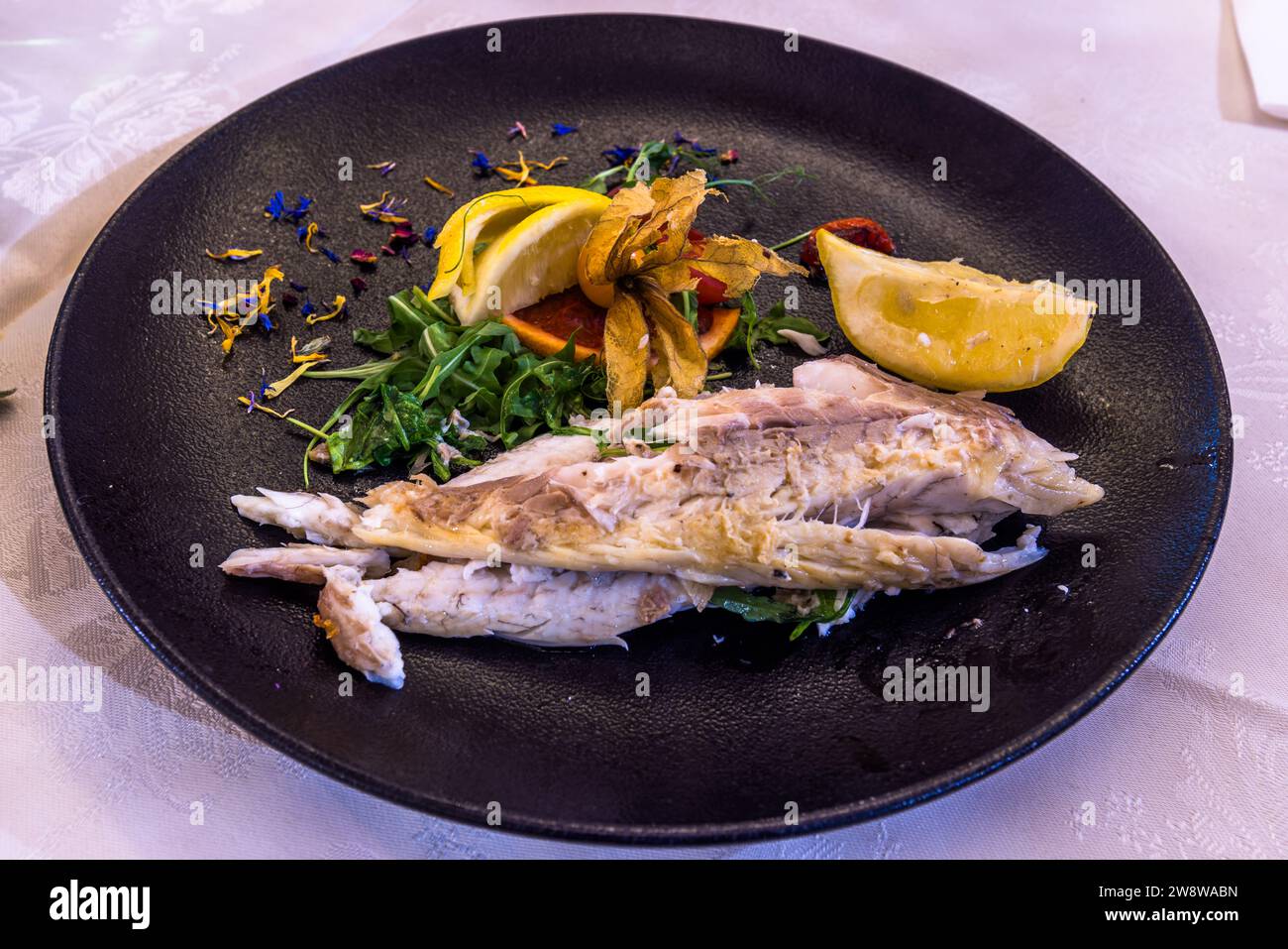 Un poisson entier grillé avec des quartiers de citron, de la roquette et des fleurs comestibles est servi au restaurant "Country Terrace" à Għajnsielem sur l'île de Gozo, à Malte. Banque D'Images