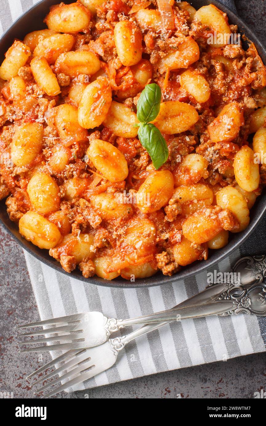 Cuisine italienne traditionnelle gnocchi de pommes de terre avec sauce bolognaise à la viande et parmesan closeup sur l'assiette sur la table. Vue verticale de dessus depuis abo Banque D'Images