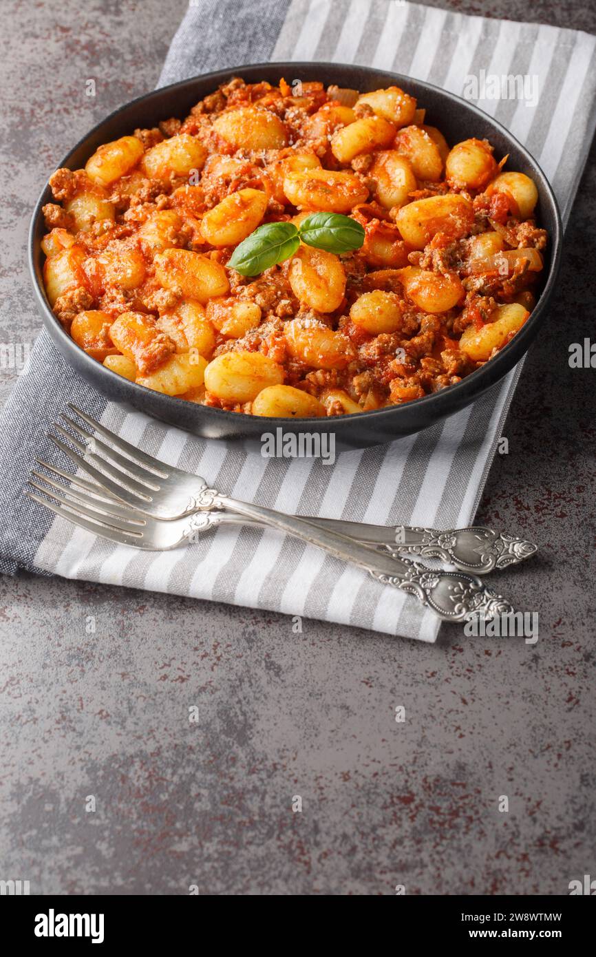 Cuisine italienne traditionnelle gnocchi de pommes de terre avec sauce bolognaise à la viande et parmesan closeup sur l'assiette sur la table. Vertical Banque D'Images