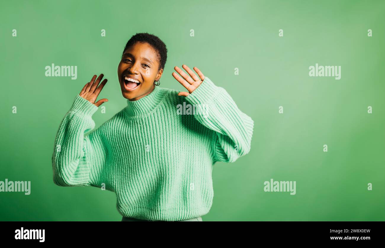 Portrait d'une jeune belle femme joyeuse portant des vêtements verts debout sur un fond vert. Jeune femme regardant la caméra. Banque D'Images