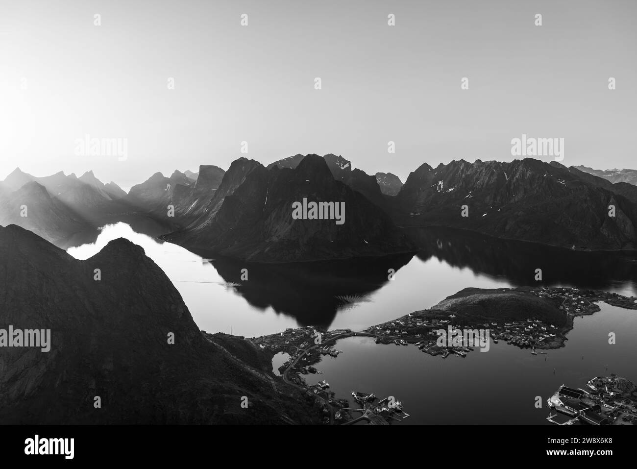 Une vue monochrome de Reinebringen révèle les contrastes saisissants entre les montagnes escarpées des îles Lofoten et les eaux réfléchissantes ci-dessous, Wit Banque D'Images