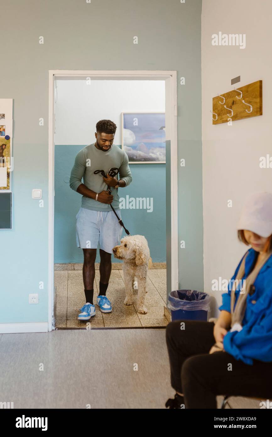 Jeune homme marchant labradoddle en attendant en clinique vétérinaire Banque D'Images