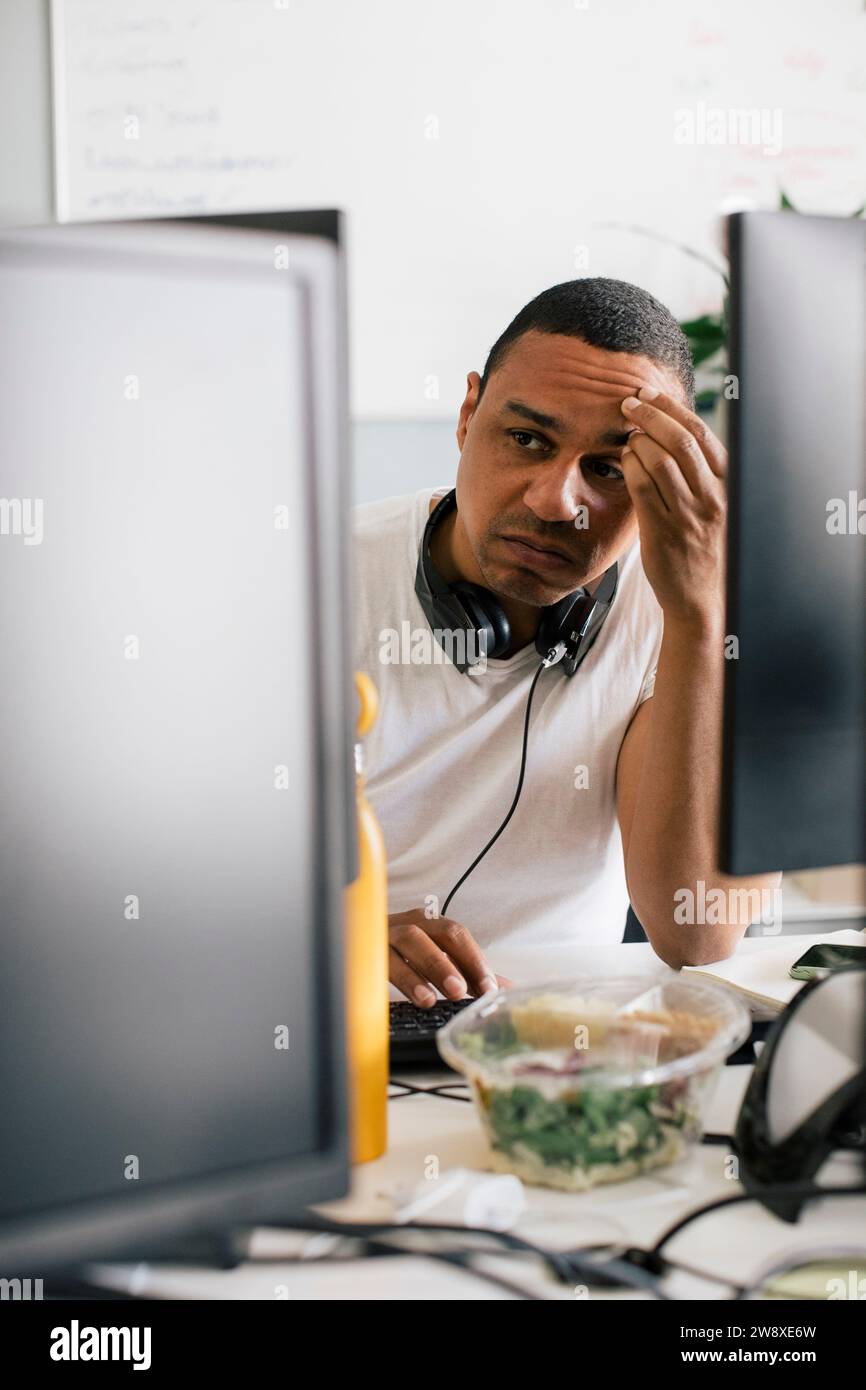 Entrepreneur masculin inquiet avec la tête dans la main assis au bureau dans le bureau Banque D'Images