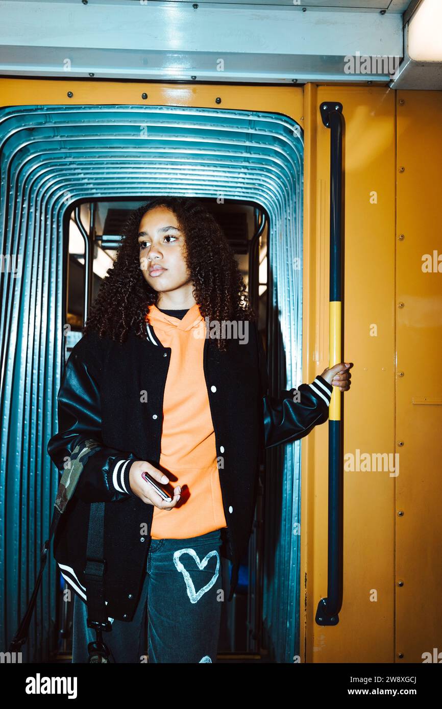 Adolescente debout à la porte du tram tout en voyageant pendant le week-end Banque D'Images