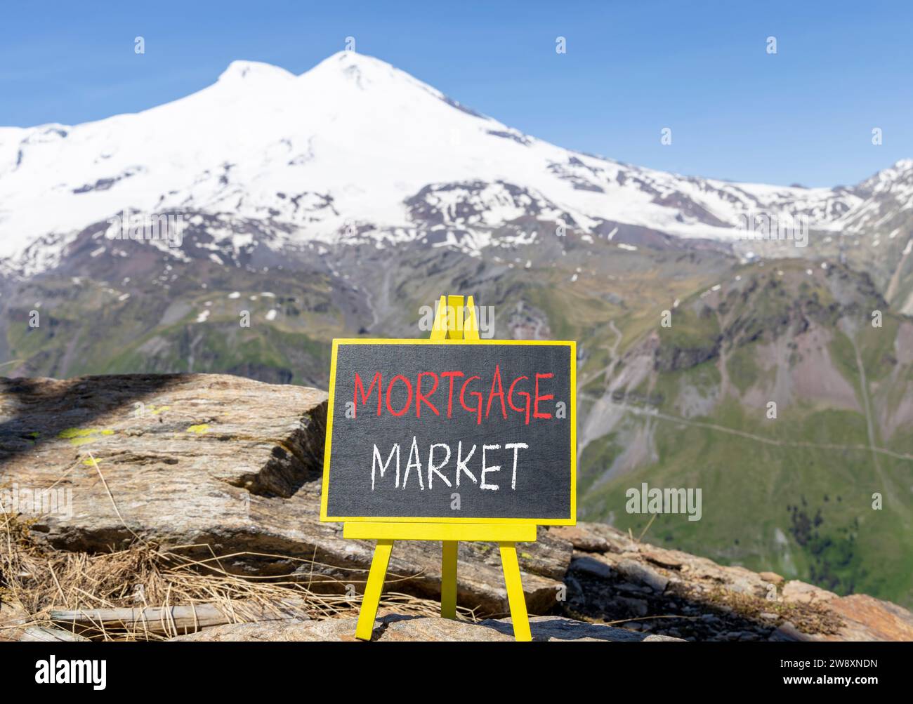 Symbole du marché hypothécaire. Mots concept marché hypothécaire sur beau tableau noir de craie. Belle montagne Elbrus fond de ciel bleu. Or Banque D'Images
