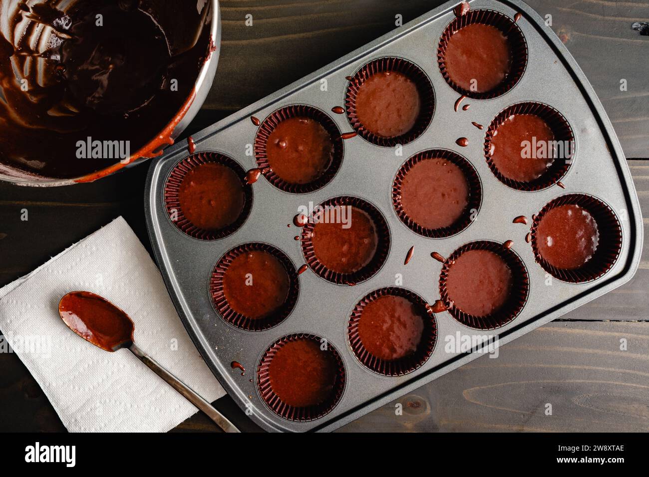 Moule à muffins rempli de pâte à cupcake au chocolat dans des tasses en papier : cupcakes au chocolat non cuits dans un moule à muffins antiadhésif avec des doublures en papier Banque D'Images