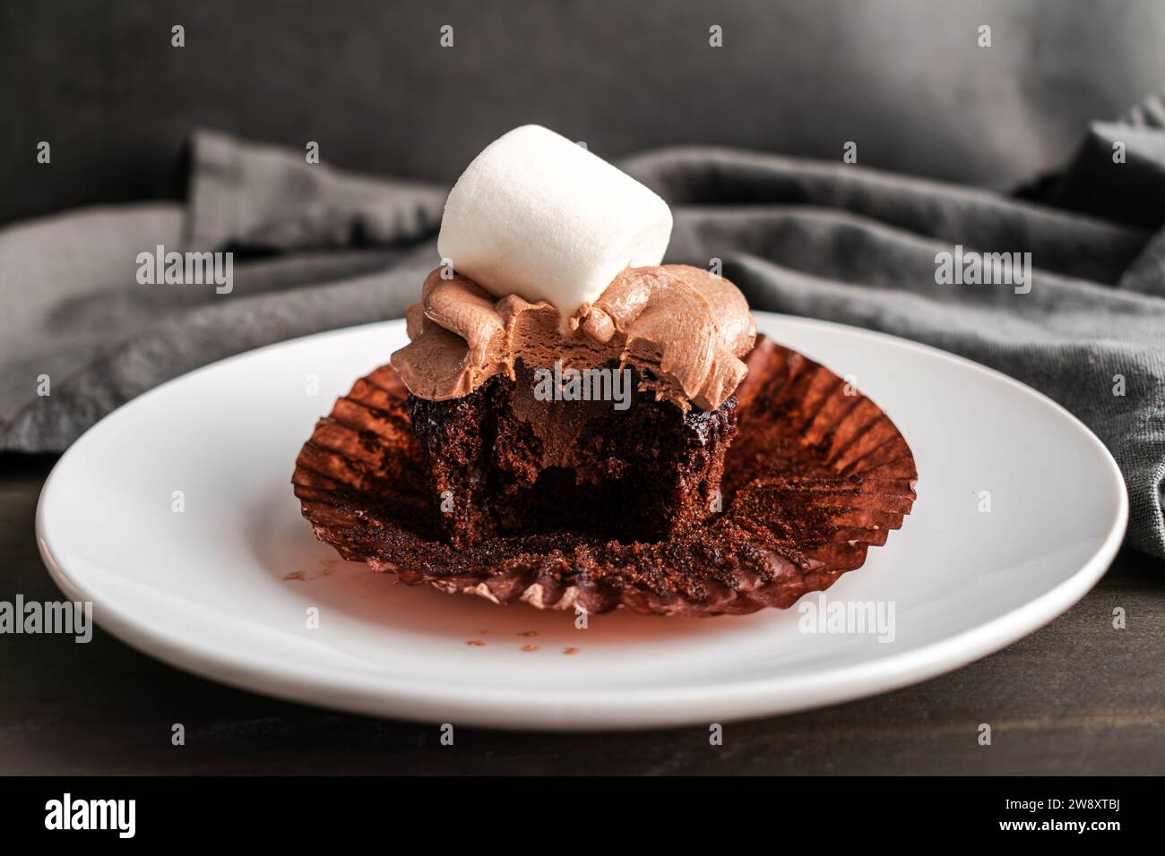 Cupcake au cacao chaud avec une bouchée prise : cupcake au chocolat chaud avec garniture de ganache au chocolat qui a été mordu Banque D'Images