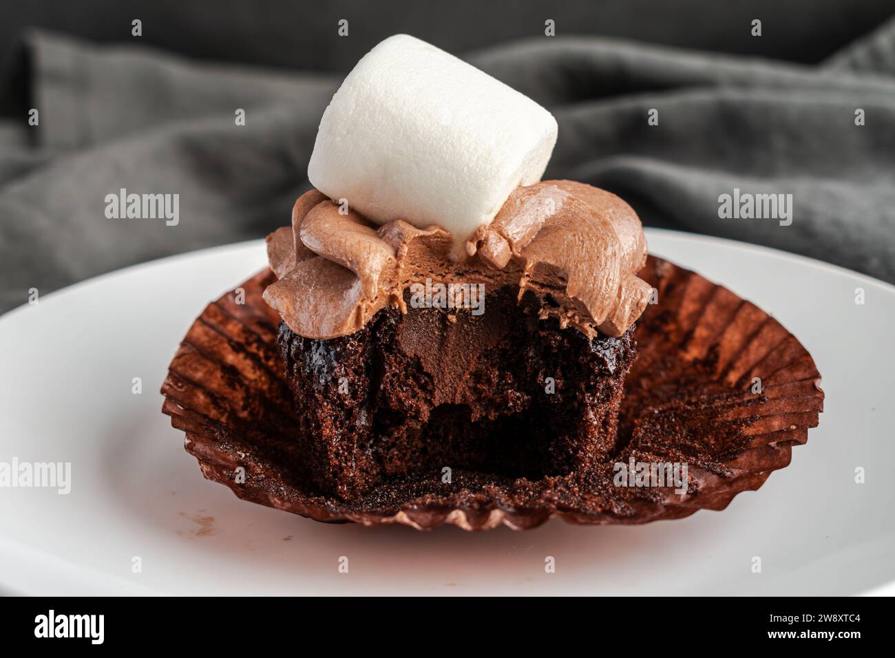Cupcake au cacao chaud avec une bouchée prise : cupcake au chocolat chaud avec garniture de ganache au chocolat qui a été mordu Banque D'Images