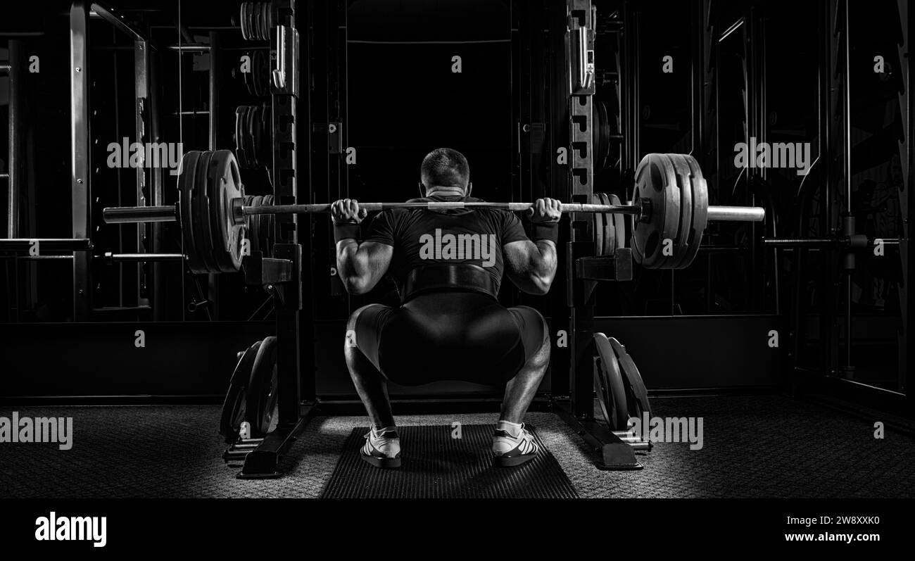 Athlète professionnel assis avec une barre sur ses épaules et se prépare à se tenir avec elle. Vue de l'arrière Banque D'Images