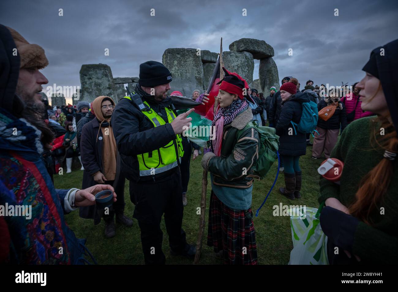 Wiltshire, Royaume-Uni. 22 décembre 2023. Célébrations du solstice d'hiver à Stonehenge : un activiste pro-palestinien s'affronte avec la sécurité qui affirme les règles du site du patrimoine contre toute manifestation politique contre les pierres. Les révélateurs, y compris les druides et les païens modernes, se réunissent à Stonehenge sur la plaine de Salisbury pour célébrer le premier jour de l'hiver - le jour le plus court et la nuit la plus longue de l'année. Crédit : Guy Corbishley/Alamy Live News Banque D'Images
