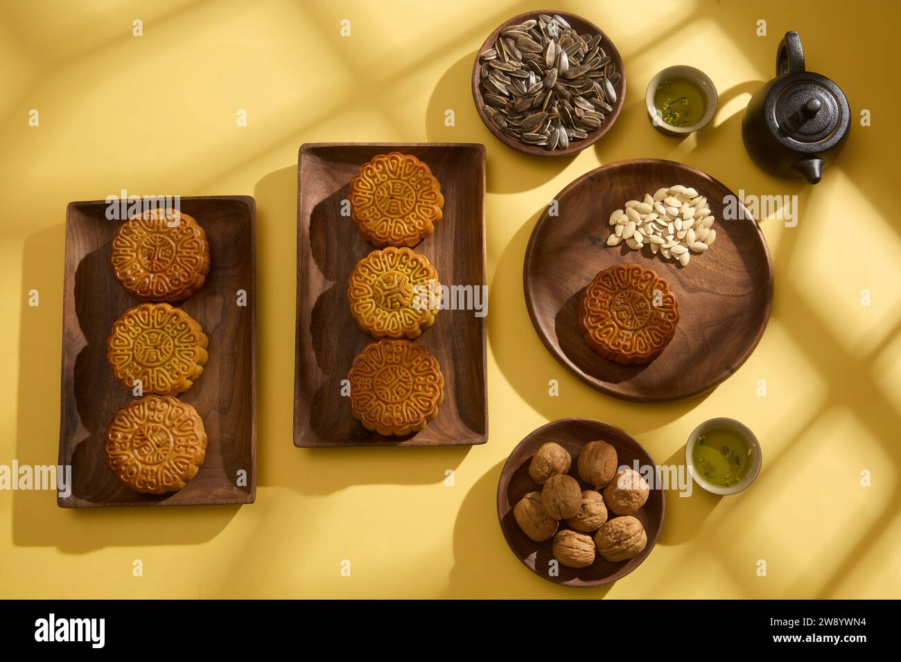 Simplicité minimale disposition des mooncakes sur fond jaune pour le Festival de la mi-automne. Sur des plateaux en bois remplis de gâteaux de lune appétissants, de graines sèches et de set Banque D'Images