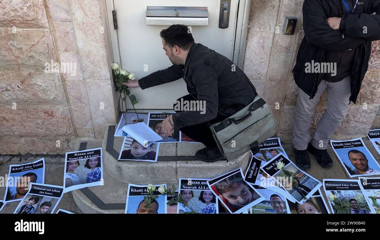 Les militants juifs israéliens pour la paix placent des fleurs et des affiches avec des portraits de Palestiniens tués par le bombardement israélien de Gaza à l’entrée du consulat américain, appelant à un cessez-le-feu et pleurant les 20 000 Palestiniens tués par le bombardement israélien de la bande de Gaza le 22 décembre 2023 à Jérusalem, en Israël Banque D'Images