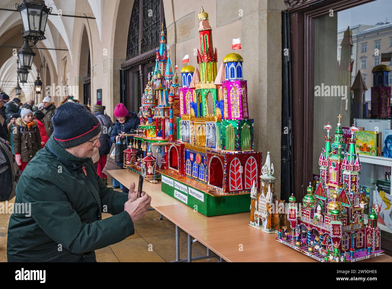 Personnes prenant des photos de Szopki (scènes de la Nativité de Noël) à l'ouverture du concours annuel en décembre, événement inclus dans la liste du patrimoine culturel de l'UNESCO, aux arcades de Sukiennice (salle des vêtements), place principale du marché, Kraków, Pologne Banque D'Images