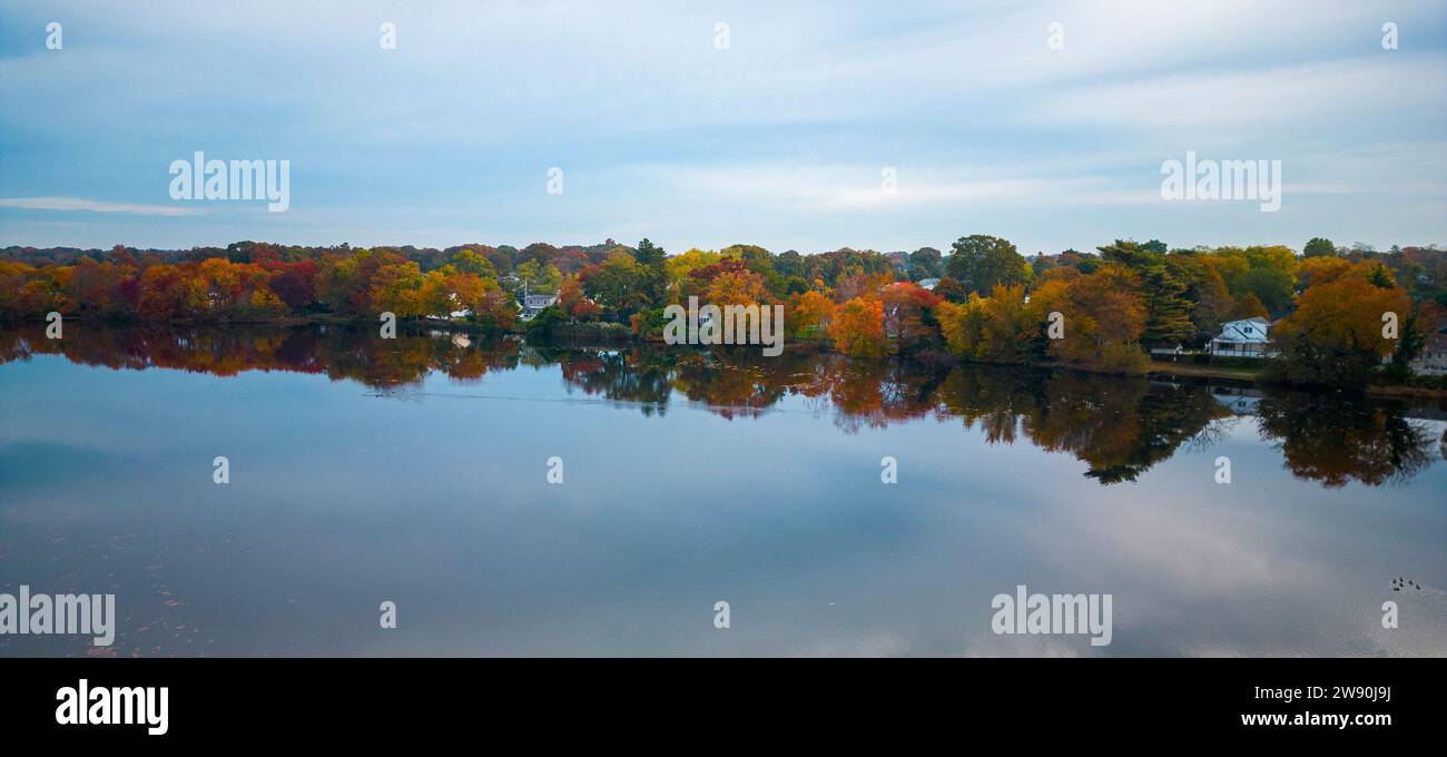 Vue d'en haut d'Un plan d'eau entouré de beaucoup d'arbres colorés se reflétant dans l'eau du lac. Banque D'Images