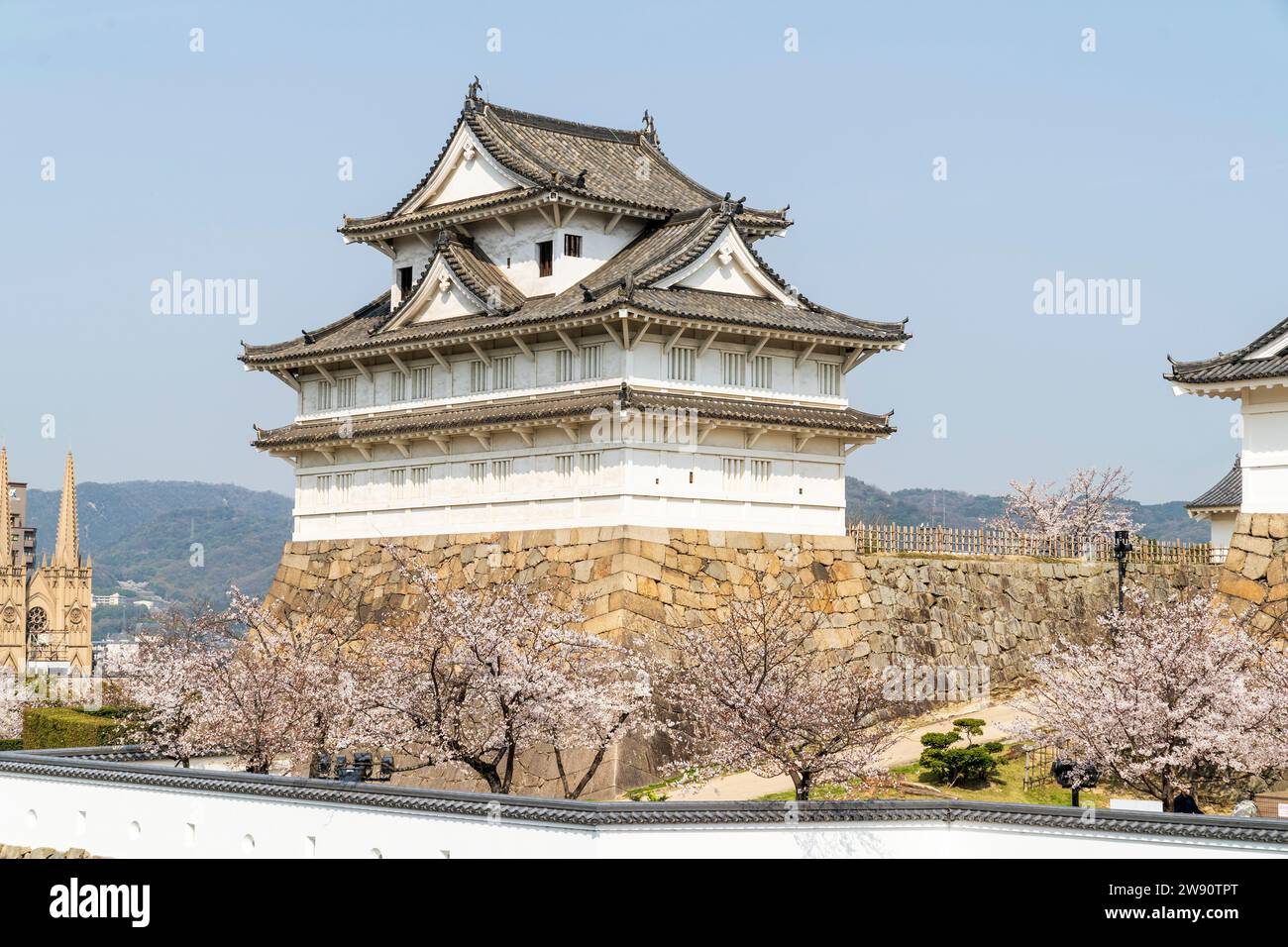 Le coin Fushimi yagura, tourelle de trois étages sur les murs de pierre Ishigaki au château de Fukuyama au Japon. Jour, avec ciel bleu, et cerisier en fleur. Banque D'Images