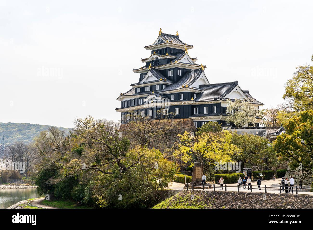 Château d'Okayama, Japon. L'impressionnant style sotogata noir garder avec ses crêtes dorées, dominant les visiteurs ci-dessous, par une journée ensoleillée de printemps. Banque D'Images