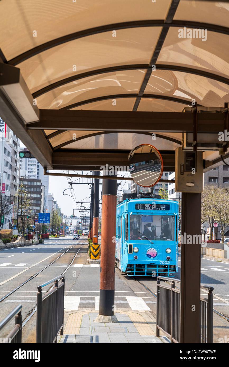 Tram sur la ligne Higashiyama approchant de l'arrêt de tramway yanagawa sur le Momotaro-odori, une rue principale à quatre voies à Okayama. Banque D'Images