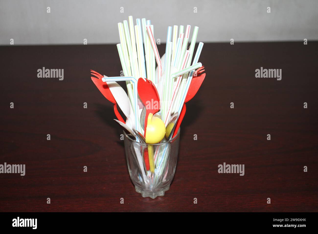 Un groupe de pailles de jus dans un verre transparent avec des cuillères de couleur rouge et jaune. Banque D'Images