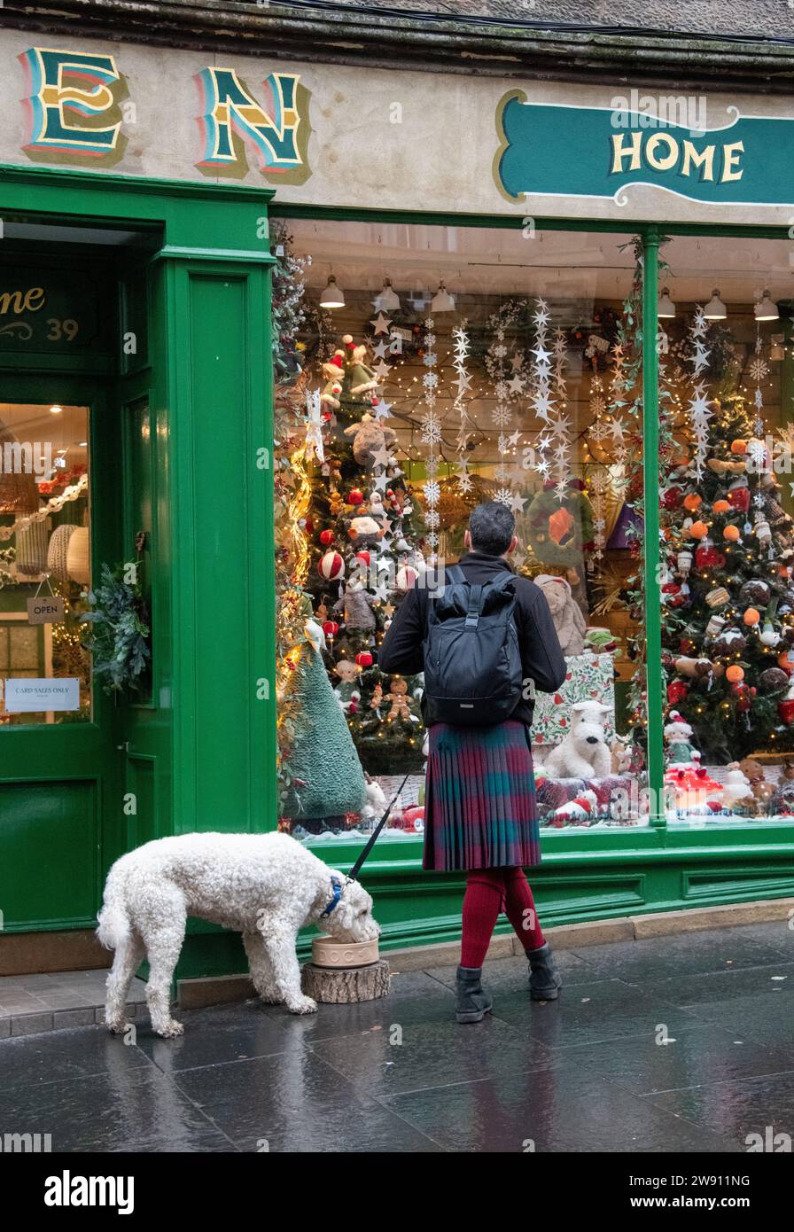 Edimbourg, Royaume-Uni. 23 décembre 2023. Un homme dans un kilt regarde dans une vitrine à Édimbourg avec son chien Credit : Thomas Faull/Alamy Live News Banque D'Images