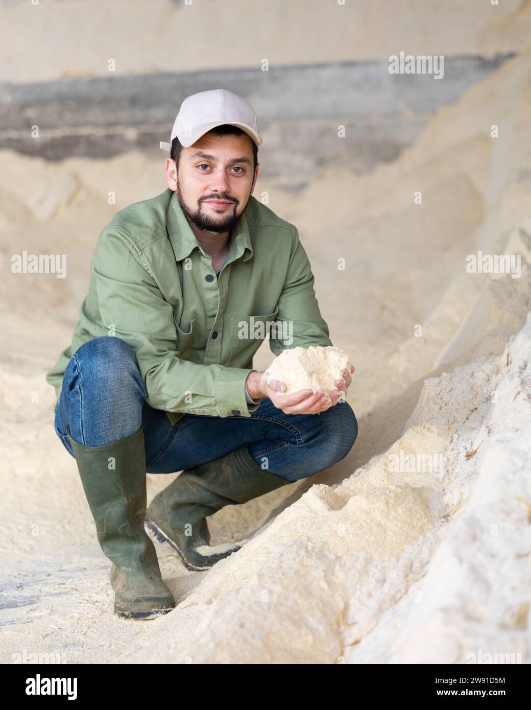 Portrait de fermier accroupi au tas de farine de maïs Banque D'Images