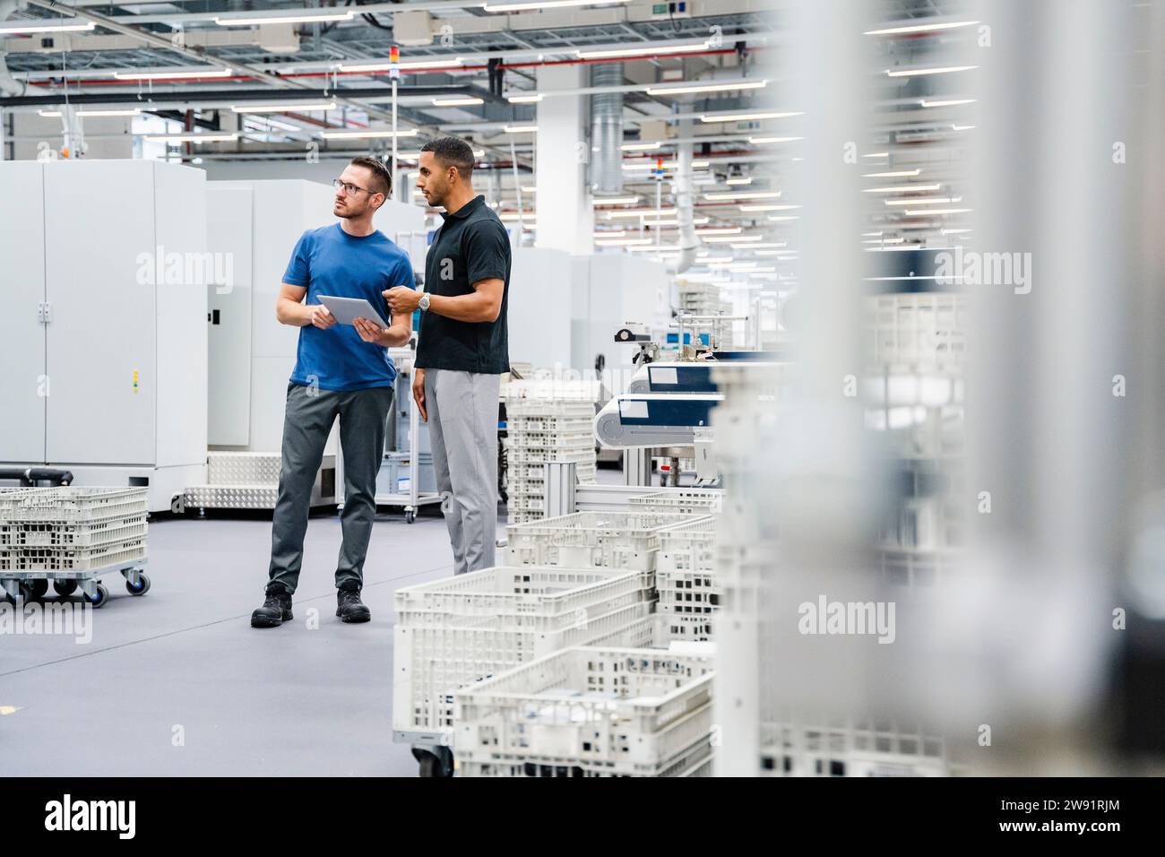 Deux collègues avec tablette numérique parlant dans une usine Banque D'Images
