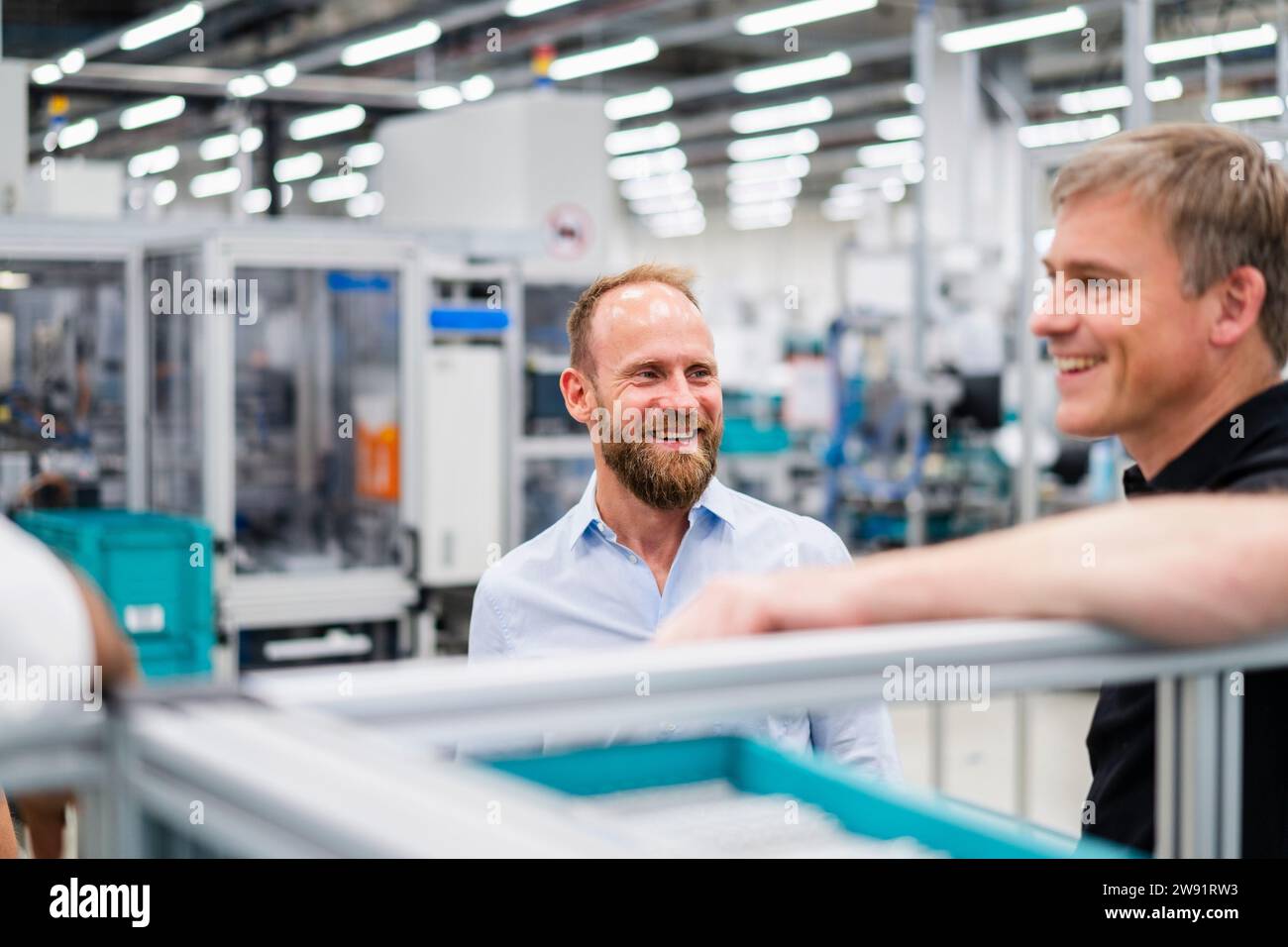 Homme d'affaires souriant regardant employé dans une usine Banque D'Images