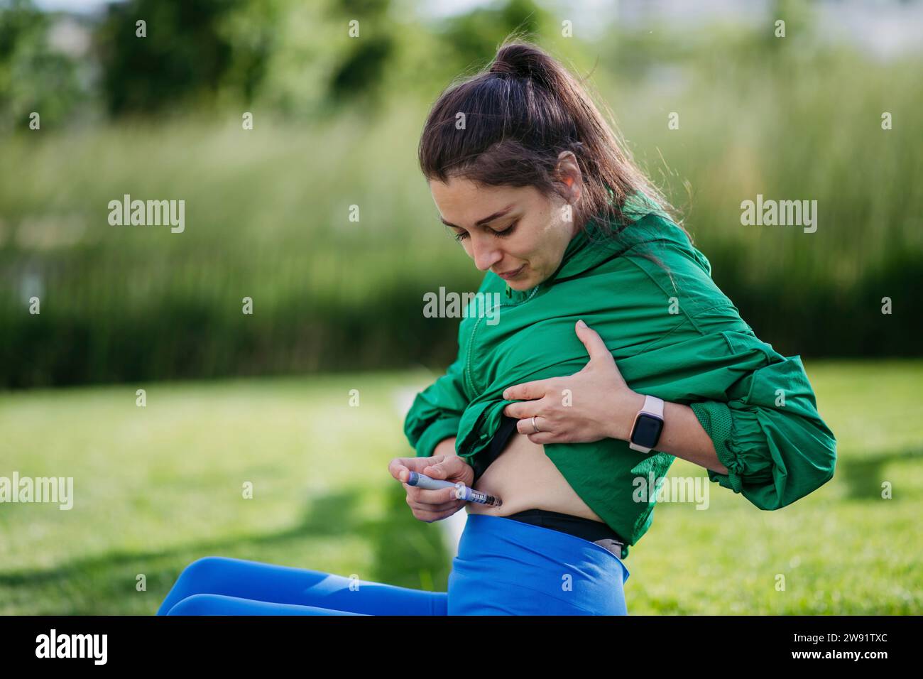 Femme diabétique injectant de l'insuline dans son abdomen avec un stylo à insuline, tandis que des exercices à l'extérieur Banque D'Images