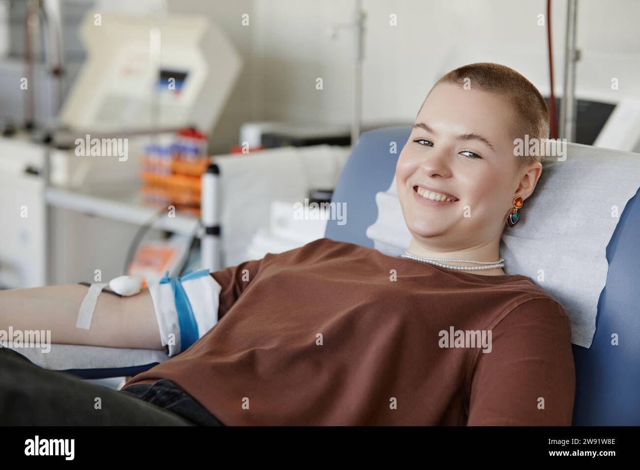 Jeune femme souriante allongée sur le canapé donnant du sang Banque D'Images