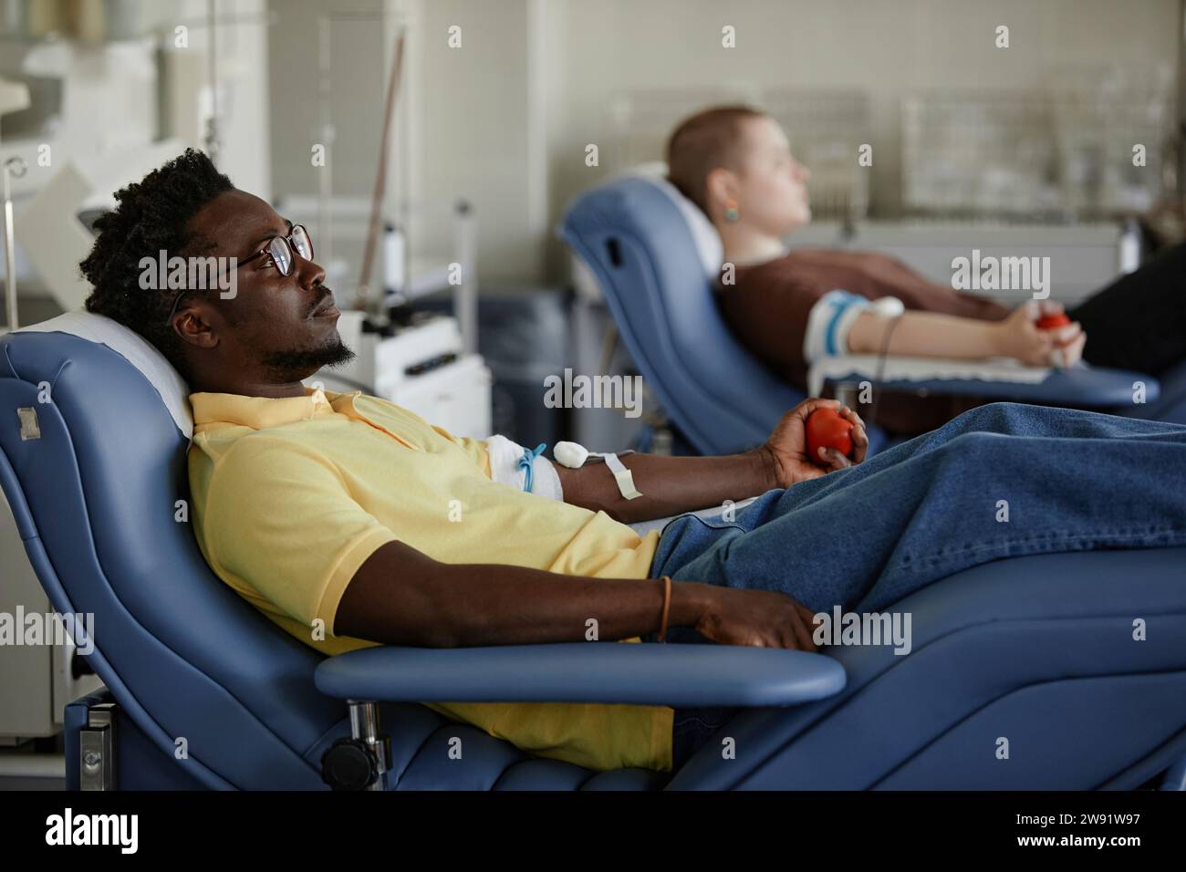 Homme allongé sur un canapé assistant à une transfusion sanguine Banque D'Images