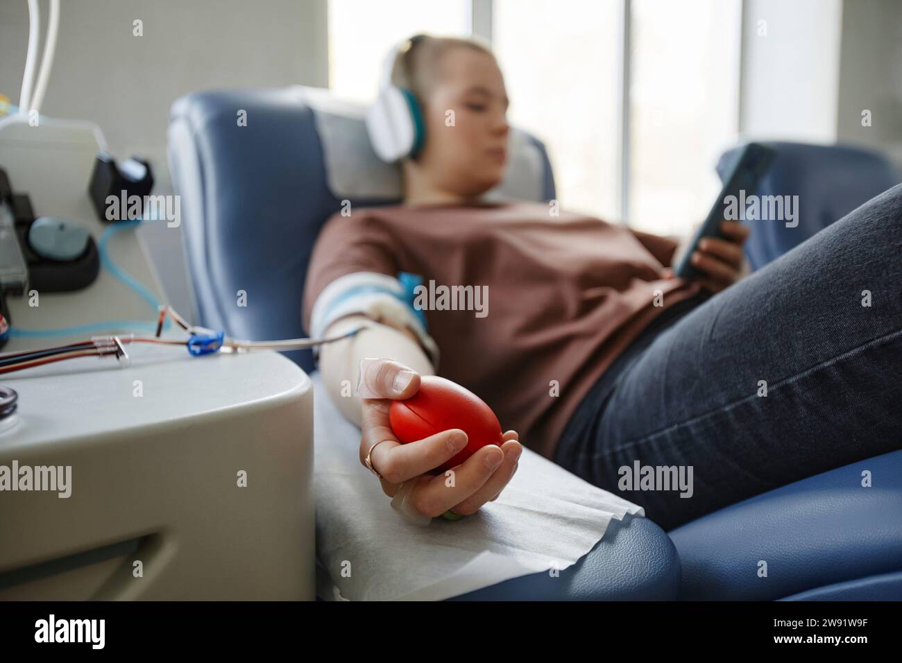 Main d'une femme tenant une balle molle couchée sur le canapé au centre de don de sang Banque D'Images