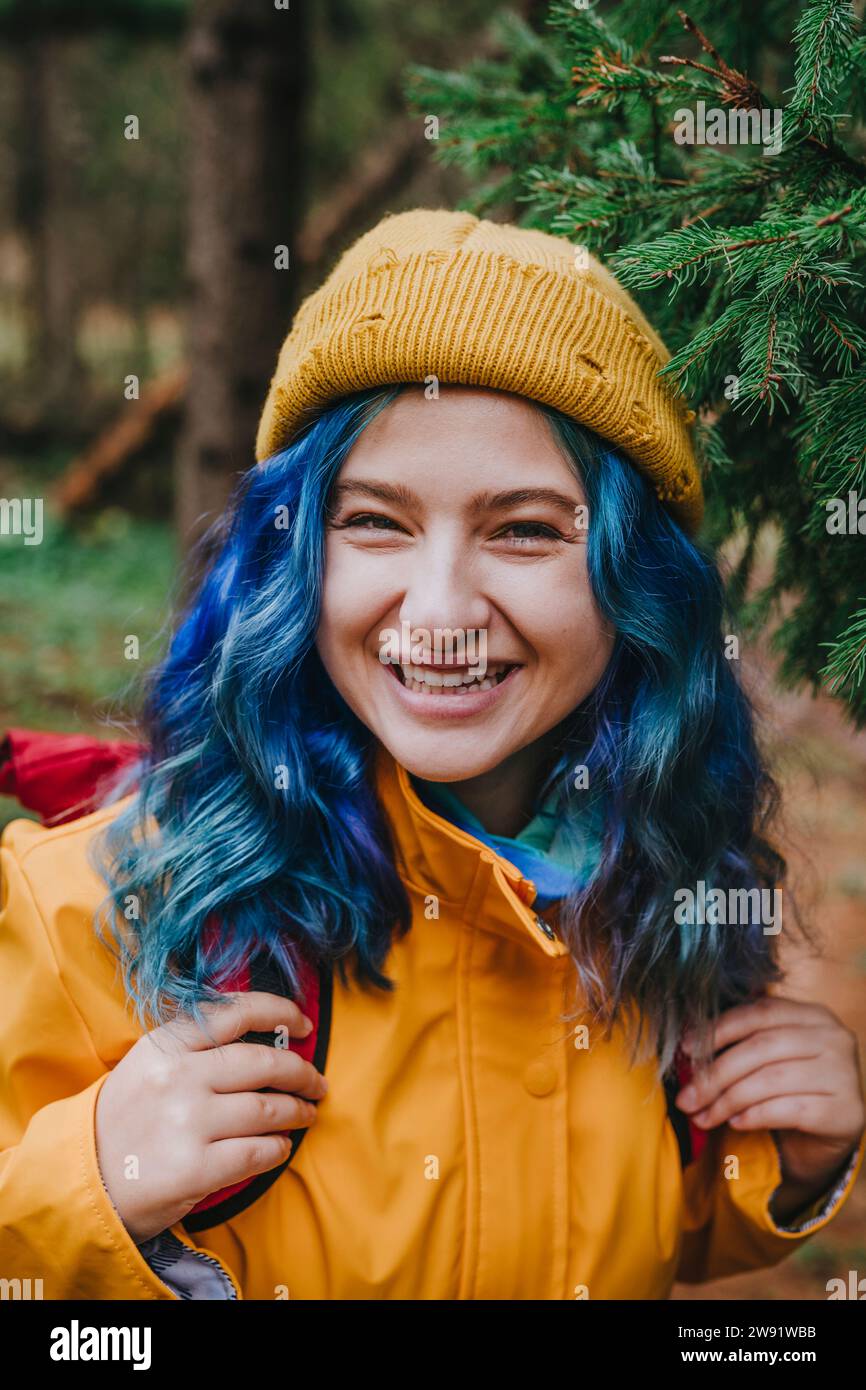 Femme heureuse portant un chapeau en tricot et portant un sac à dos dans la forêt Banque D'Images