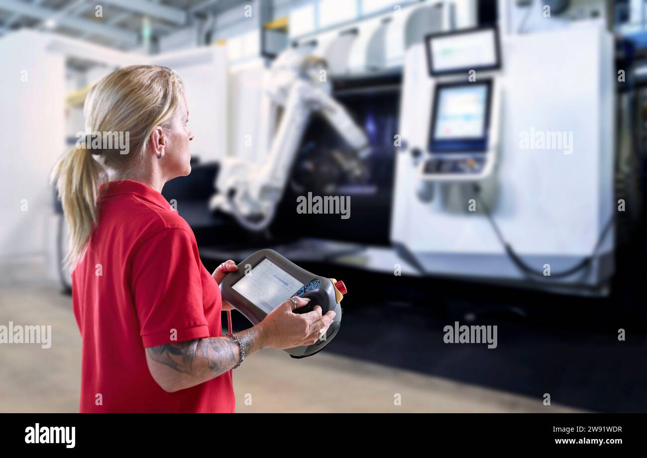 Technicien utilisant le bras robotique et la machine par le biais d'une tablette PC en usine Banque D'Images