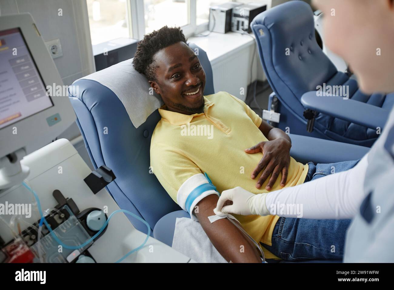 Donneur souriant parlant à un travailleur de santé au centre de don de sang Banque D'Images