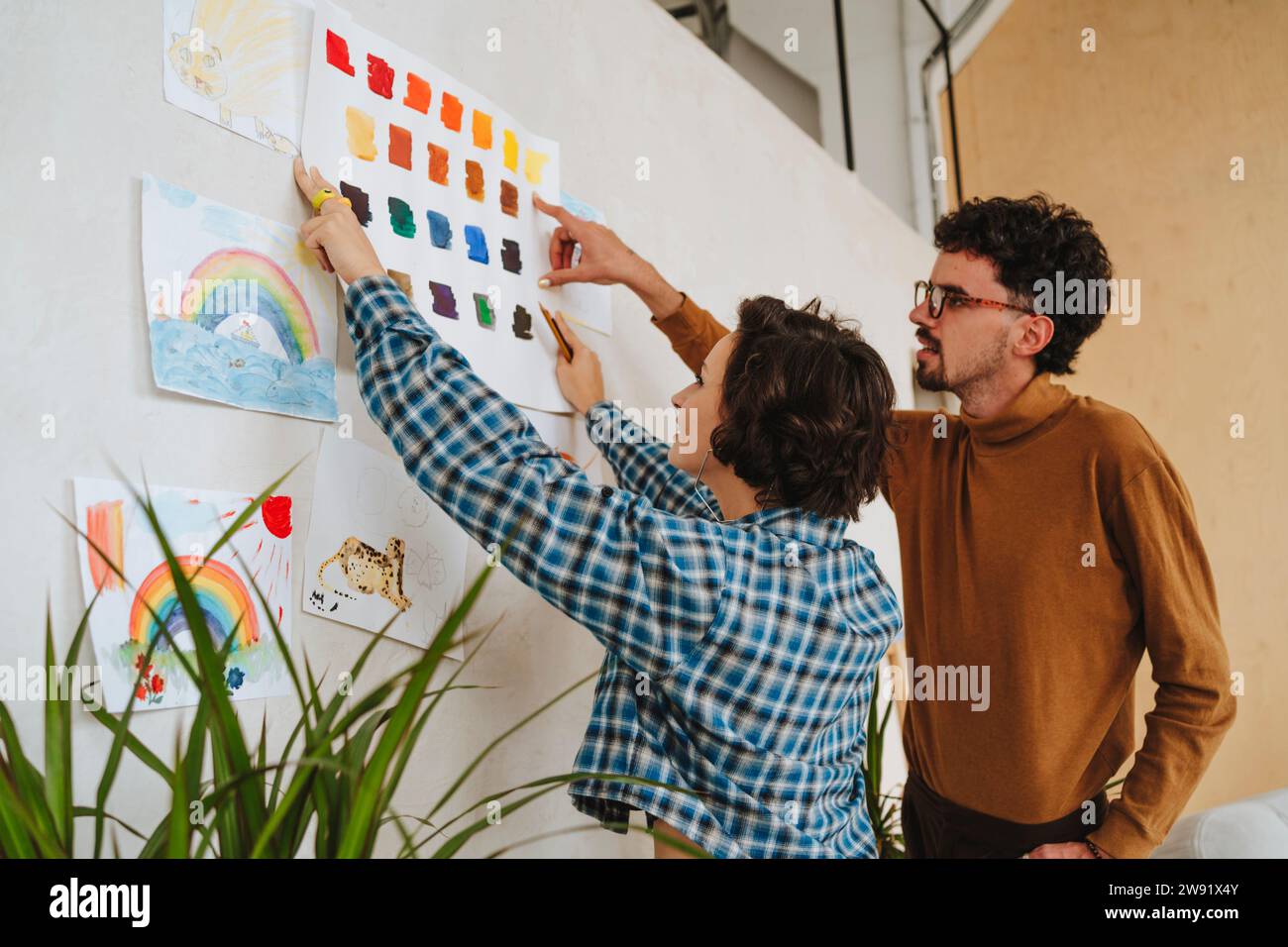 Illustrateurs de design collant des échantillons de couleur sur le mur au bureau Banque D'Images