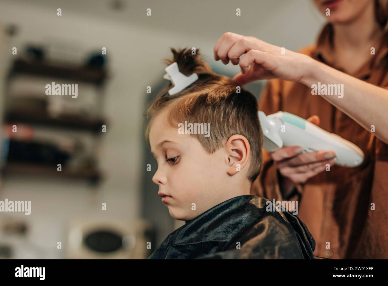 Garçon se faisant couper les cheveux par mère à la maison Banque D'Images