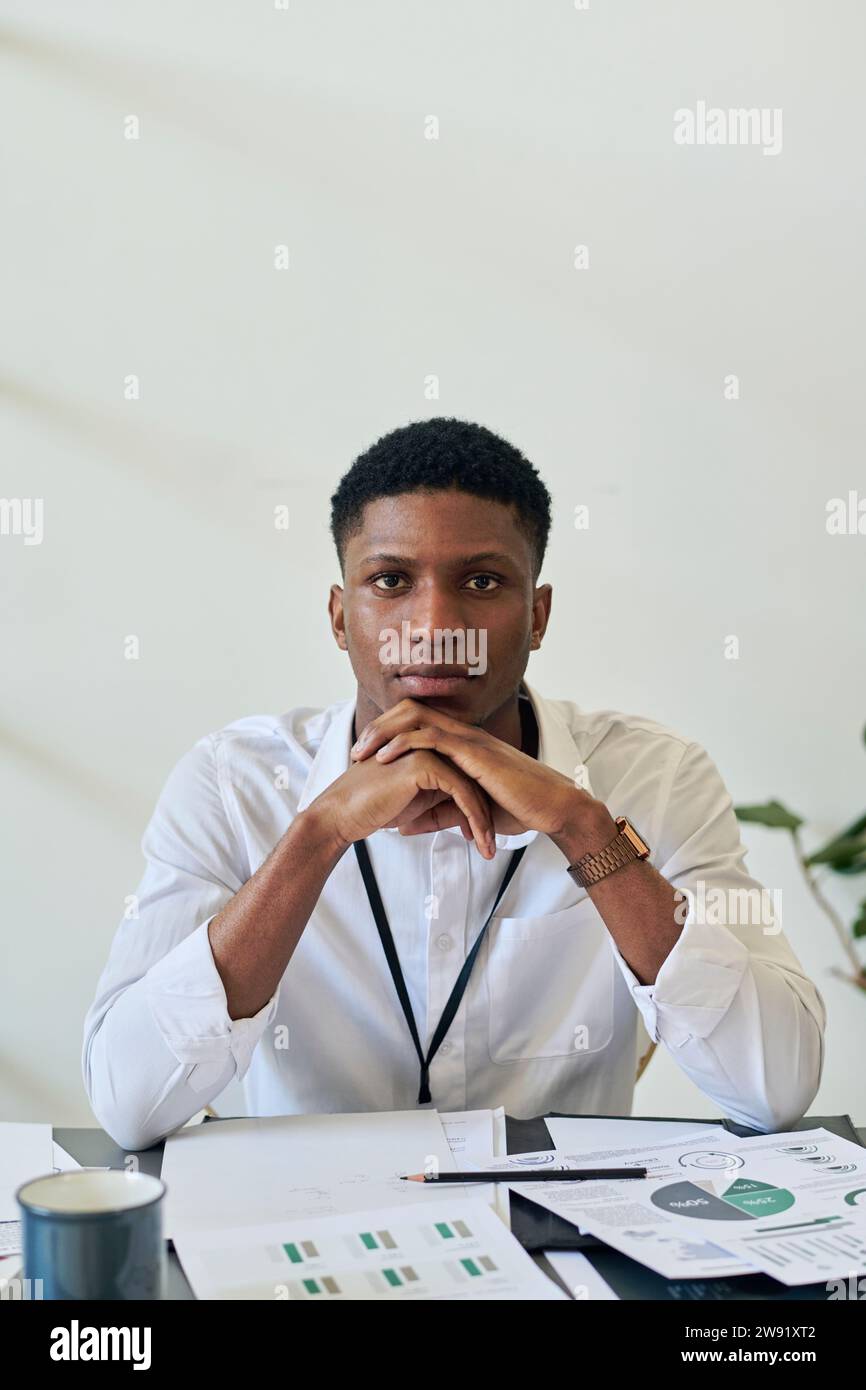 Jeune homme d'affaires assis avec des graphiques et des tableaux dans le bureau Banque D'Images
