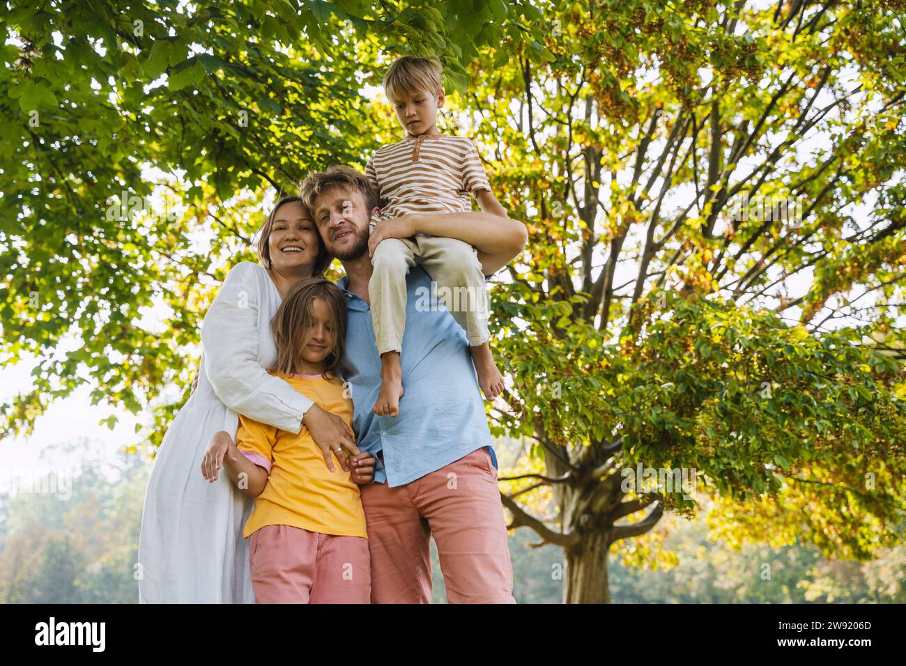 Homme portant son fils sur l'épaule debout avec sa famille au parc Banque D'Images