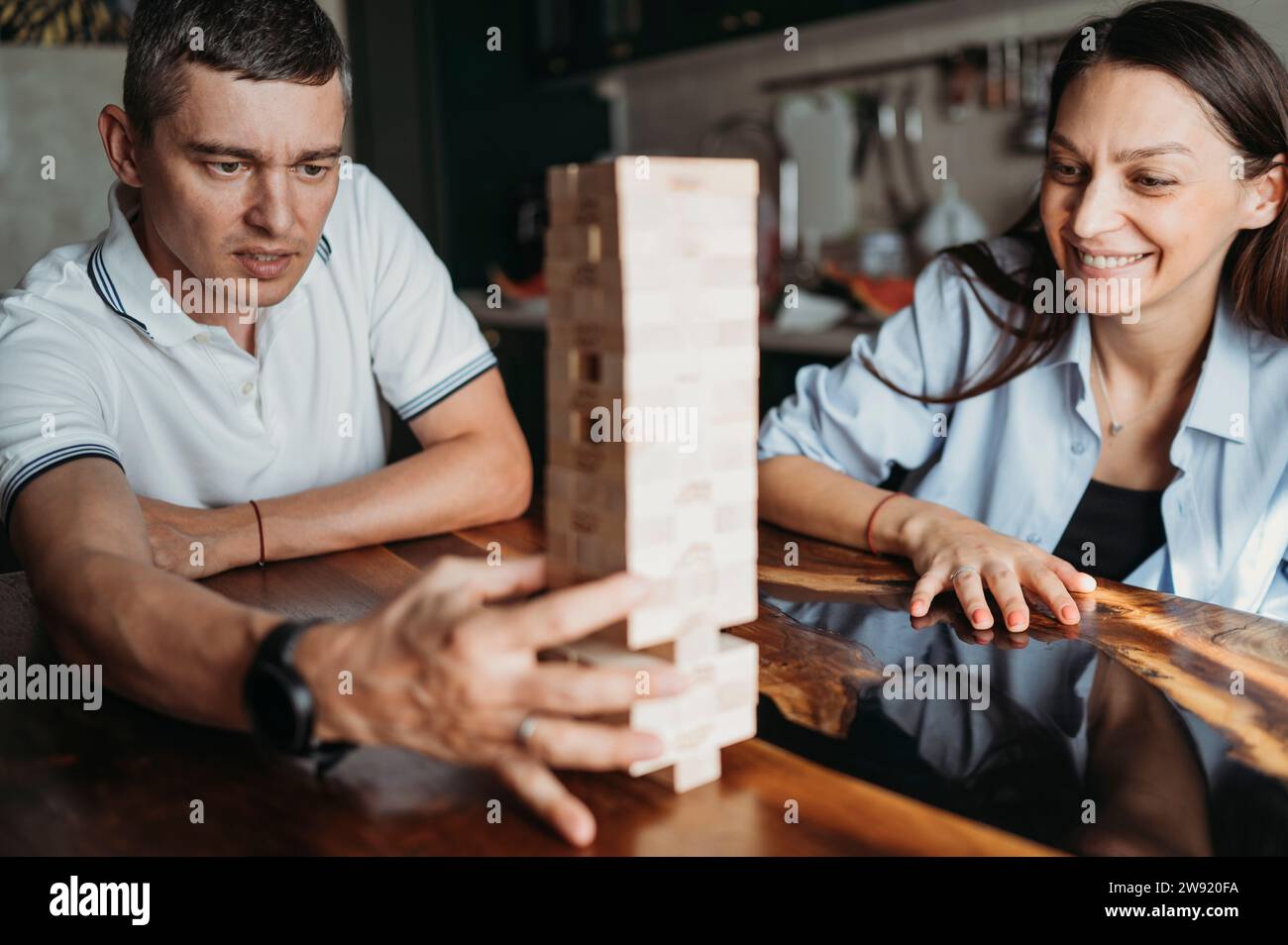 Homme souriant et femme jouant au jeu de retrait de bloc à table Banque D'Images