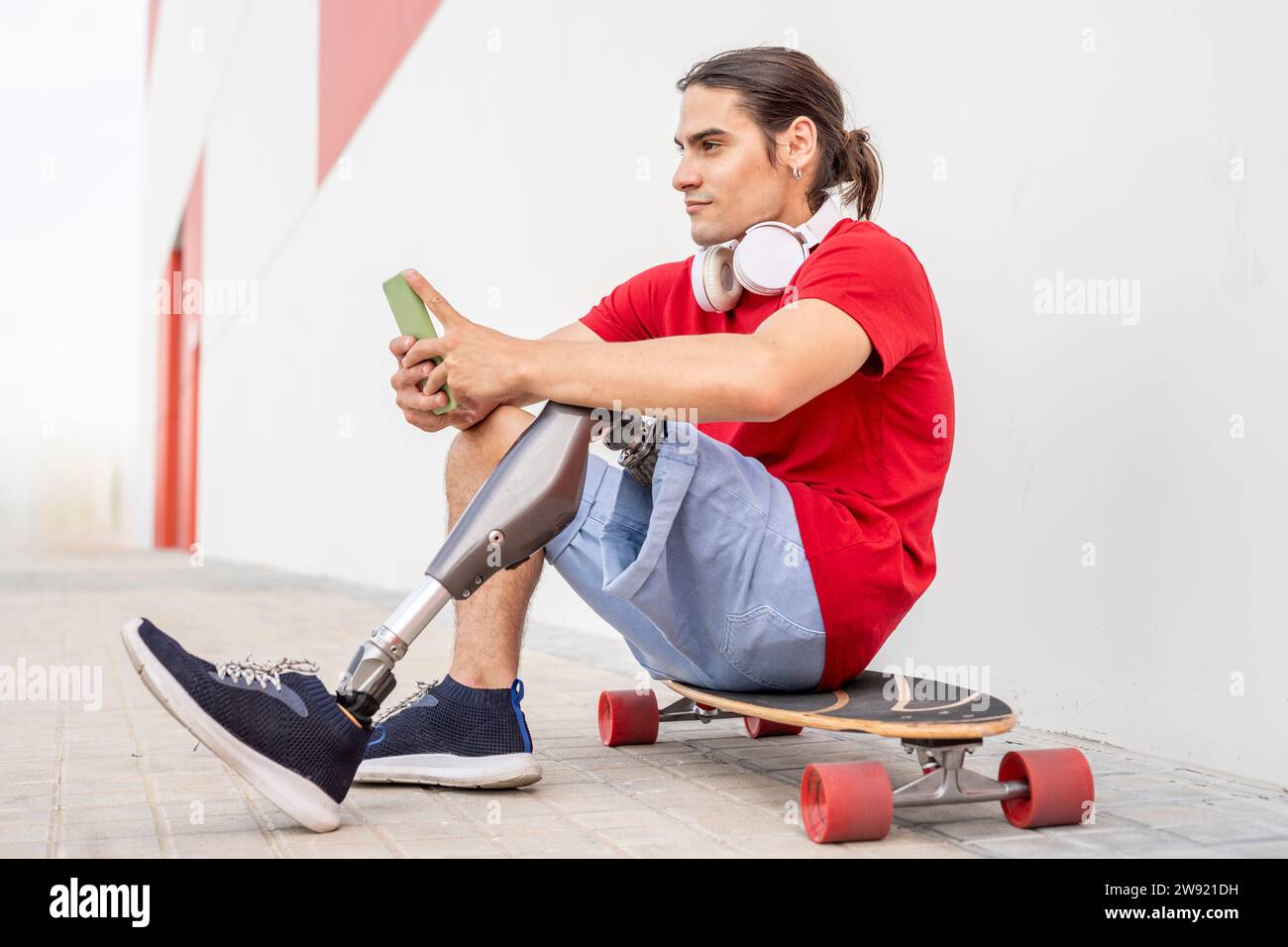 Homme réfléchi avec handicap assis sur le skateboard Banque D'Images