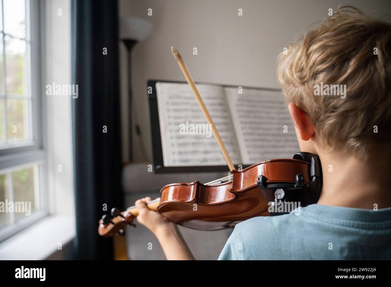 Garçon pratiquant le violon avec partition à la maison Banque D'Images
